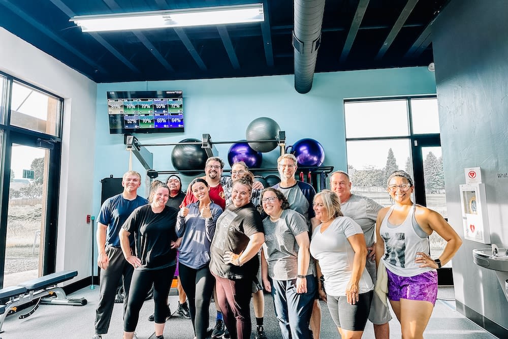 A welcoming group of adults posing together in a supportive gym environment to represent the kind of community many Gateway Hills members want.